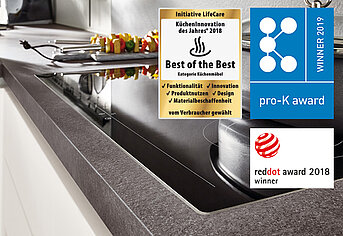 Moderne Küchenarbeitsplatte mit integriertem Spülbecken, verziert mit renommierten Designpreisabzeichen, die für hohe Qualität und Innovation im Küchendesign stehen.