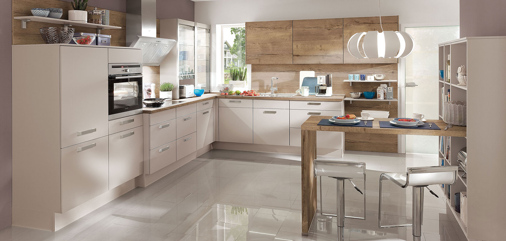 Moderne Kücheninnenräume mit eleganten weißen Schränken, Holzakzenten und Edelstahlgeräten, beleuchtet von natürlichem Licht und eleganten Pendelleuchten.