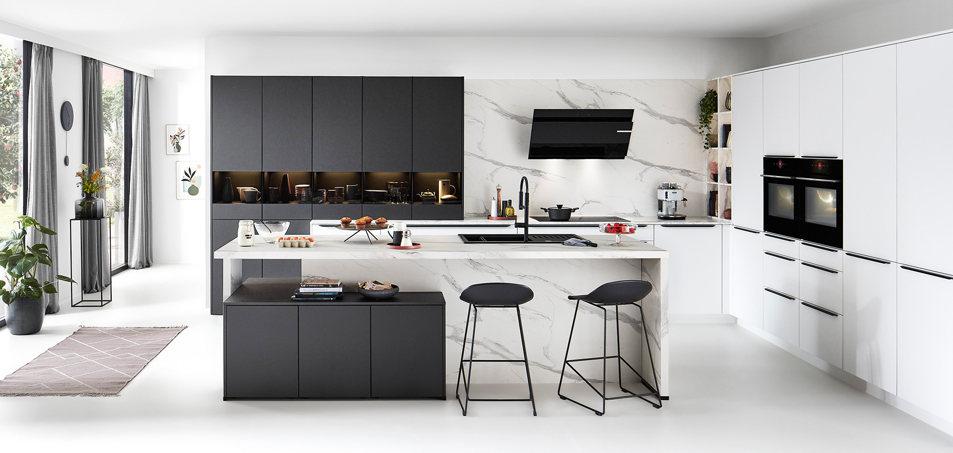 Moderne Küche mit klaren Linien, die weiße Schränke, schwarze Akzente, Marmor-Rückwand, integrierte Geräte und eine zentrale Insel mit Barhockersitzplätzen präsentiert.