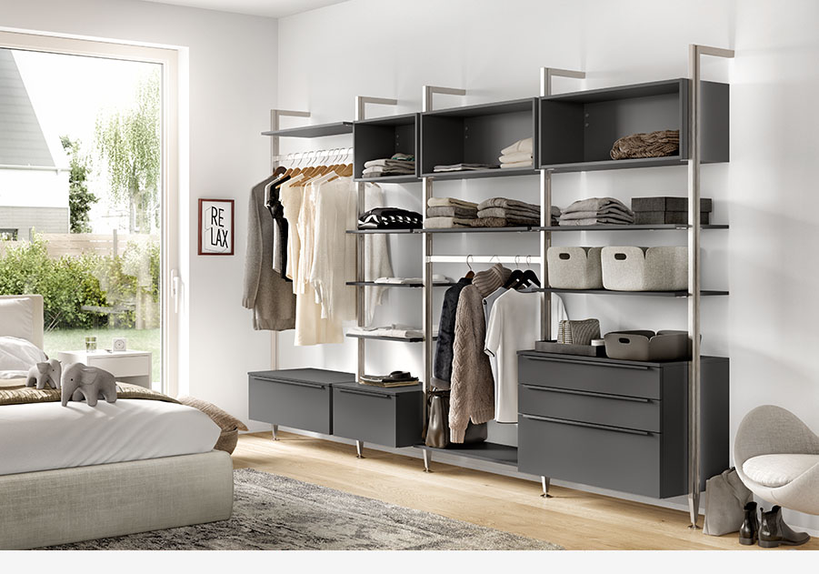 Moderner, organisierter begehbarer Kleiderschrank mit offenen Regalen, Schubladen und Aufhängemöglichkeiten, der eine neutrale Farbpalette und ein "RELAX"-Schild für eine ruhige Atmosphäre präsentiert.
