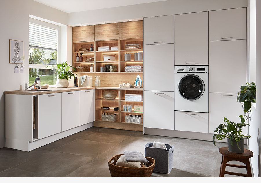 Zeitgemäße Küche mit weißen Schränken, Holzregalen, integrierten Geräten und reichlich Tageslicht, das einen gemütlichen, stilvollen Raum schafft.