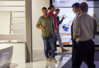 Gruppe von Menschen, die in einem modernen Einzelhandelsgeschäft mit hellen, beleuchteten Displays und zeitgemäßem Design miteinander sprechen.