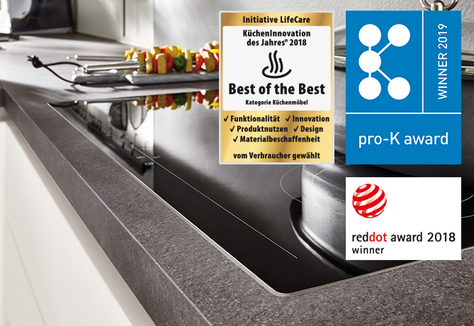 Moderne Küchenarbeitsplatte mit integriertem Spülbecken, verziert mit renommierten Designpreisabzeichen, die für hohe Qualität und Innovation im Küchendesign stehen.