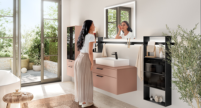 Elegantes modernes Badezimmer mit einer Frau, die ihr Spiegelbild in einem Spiegel über einem schicken Waschtisch bewundert, während natürliches Licht durch ein großes Fenster hereinströmt.